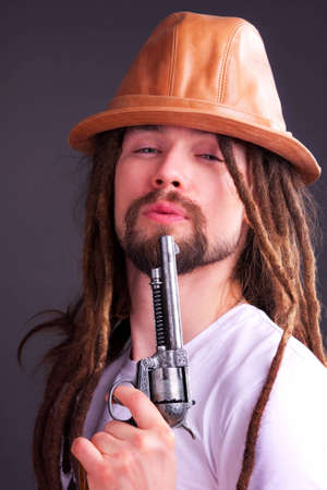 Dour guy wearing a hat holding a gun