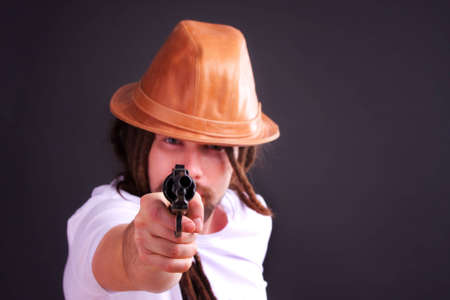 Dour guy wearing a hat holding a gunの写真素材