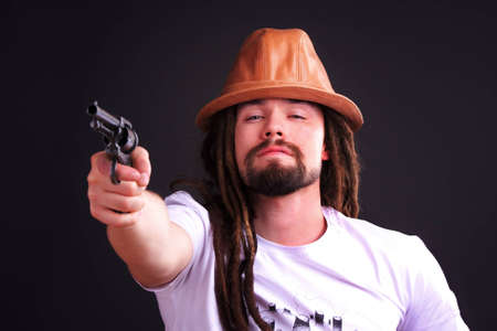 Dour guy wearing a hat holding a gunの写真素材