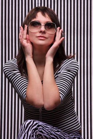Cute girl in a striped clothes and sunglasses on the striped backgroundの写真素材