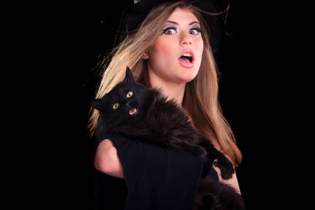 Beautiful girl dressed as a witch holding catの写真素材