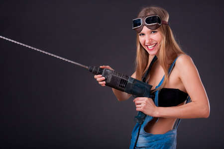 Girl with a drill in building overallsの写真素材