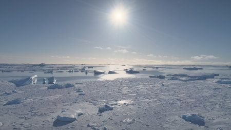 Aerial Flight Over Antarctica Ocean, Icebergs. Sun Lights Above the Frozen Water. Ice Pieces...