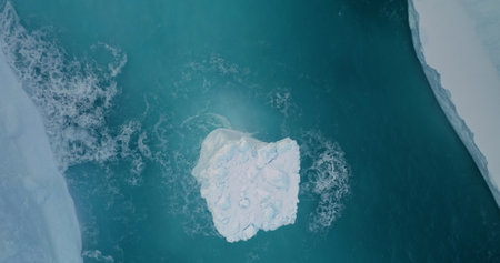 Antarctic iceberg top down view washed by blue ocean waves. Melted glacier in ice canyon of South...