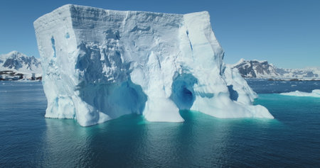 Huge Antarctic iceberg drift blue ocean sunny day. Giant ice glacier at polar nature environment....