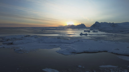 Dawn over Antarctic coast. Polar night sunset. Ocean covered ice. Top above aerial view. Antarctica...