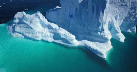 Amazing Antarctica iceberg turquoise water top down view. Giant towering glacier floats in cold...