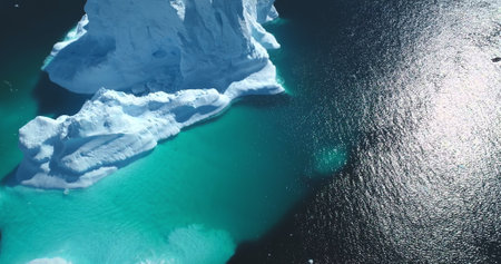 Massive iceberg melting, underwater ice formation floating turquoise ocean. Snow covered white and...