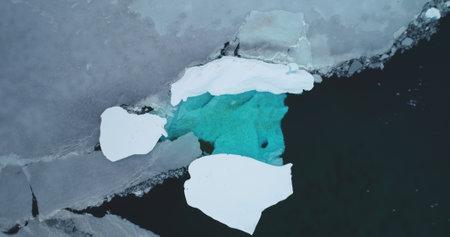 Antarctica blue water melting ice floe drift polar ocean. Aerial top down view cracked iceberg cave...