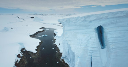 Aerial panorama towering high glacier over ocean bay canyon in Antarctica. Winter landscape wild...
