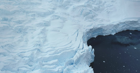 Aerial panorama glacier snow mass wall in Antarctica towering cold polar ocean. Massive snow covered...