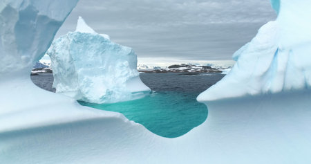 Cracked hole in melting iceberg in Antarctica ocean close up. Drone fly inside frozen glacier cave...