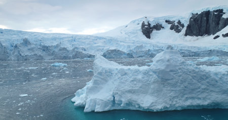 Winter mountains towering polar ocean bay in Antarctica. Melting icebergs glacier floating cold water. Aerial panorama untouched wilderness South Pole seascape. Ecology, climate change, global warmingの写真素材