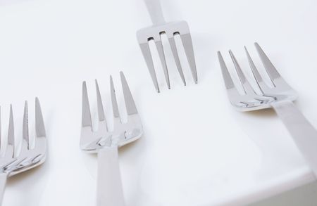 Forks on a white plate. Close-up.
