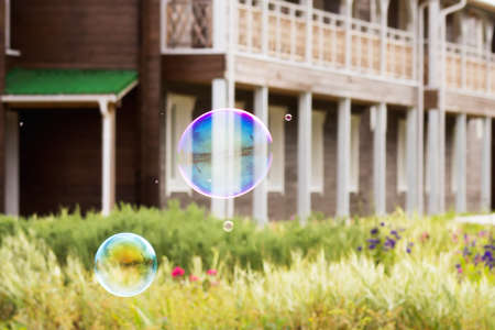 Focus on the bubbles and the hand. Soap bubbles on a background of a wooden house