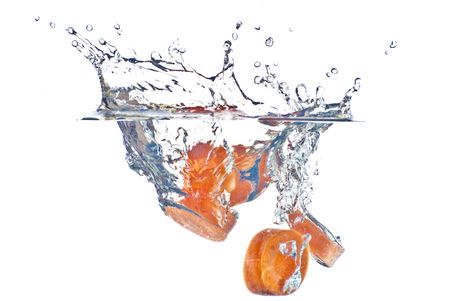Red carrot abstract splashing in the clear blue water - isolated on white backgroundの写真素材
