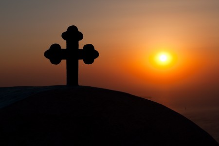 Cross on the roof of a church during sunset in Santorini islandの写真素材