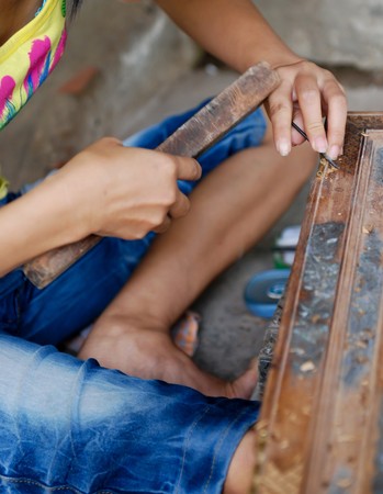 Craftsman is carving  wood to create figures  with details