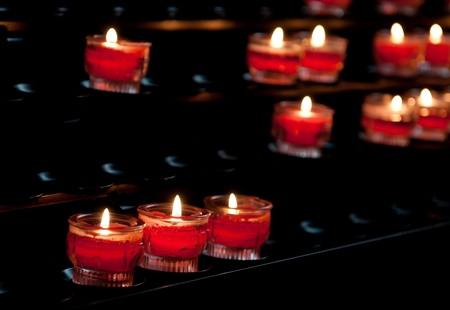 Red candle lights with flames in a churchの写真素材