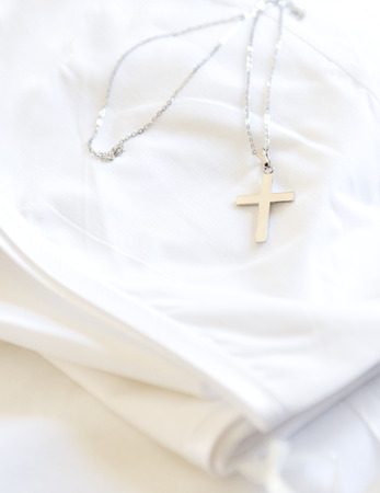 Silver christian cross on white cloth  の写真素材