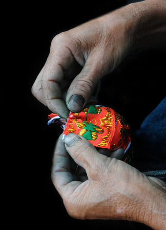 Old Woman knitting a small red wallet. Vietnam, Asia.の写真素材