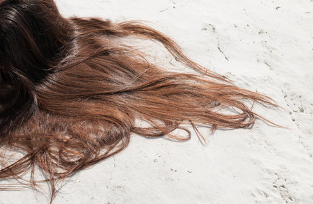 Brown hair of a yong teenage spread over a white surfaceの写真素材