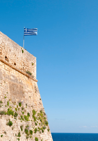 Greek flag waving  on  Rethymno  Venetian fortezza, citadel, in Crete Greece. Clear blue sky and ocean at the  background.のeditorial素材