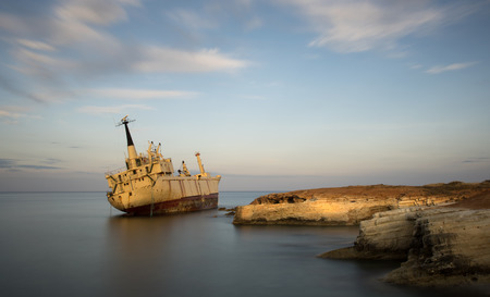 Abandoned Ship on the rocky coast  with beautiful blue and orange morning colors creating an exotic seascape at Paphos area in Cyprus. Image taken with long exposure.の写真素材
