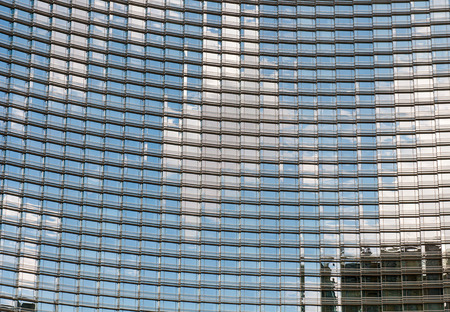 Modern glass skyscraper building architecture abstract with blue cloud reflections on the glass...