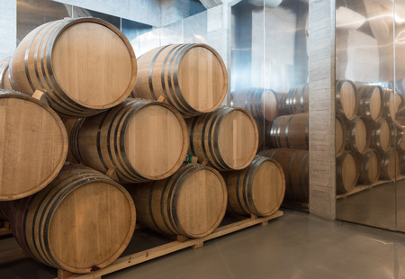 Wine wooden barrels stacket in the basement of the cellar of a winery