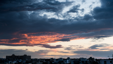 Dramatic stormy sky with red and blue clouds just before the sunset above the city of  Nicosia, Cyprusの写真素材