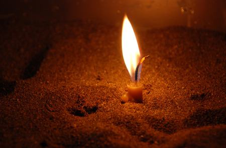 Church candle burning in sand. Symbol of religion hope and faith 