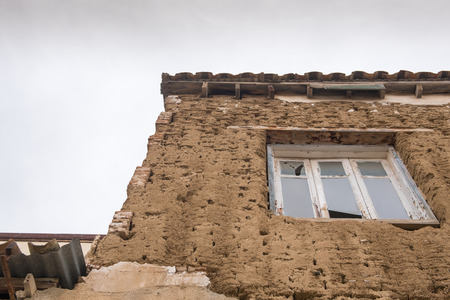 Ruins of an Abandoned house with clay bricks and a broken closed windowの写真素材