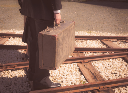 Young couple with vintage suitcase walking on the trainlines ready for a journey.の写真素材