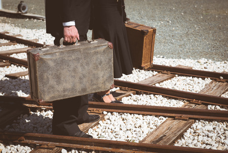 Young couple with vintage suitcase walking on the trainlines ready for a journey.の写真素材