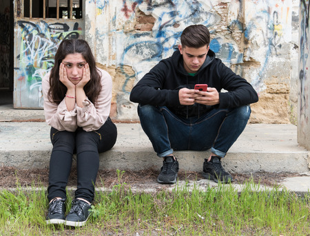 Young teenage boy talking on the mobile phone and ignoring the girl. Concept of mobile addiction