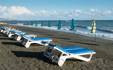 Empty beach umbrellas and chairs on an empty sandy coast early in spring at Limassol Cyprusの写真素材