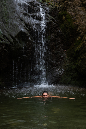 Young beautiful teenage girl swimming and enjoying the cold waterfall water. Millomery waterfalls Cyprusの写真素材