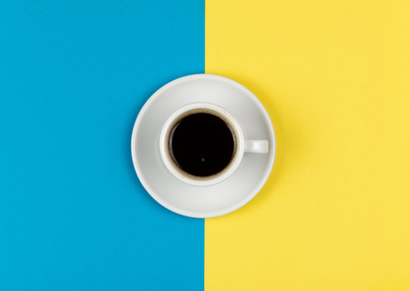 Espresso  coffee on white coffee mug resting on a yellow and blue background