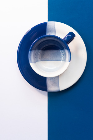 Blue and White empty coffee mug resting on a blue and white backgroundの写真素材