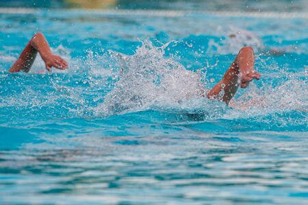 Unrecognized athletes swimming freestyle on a swimming pool during a waterpolo championship gameの写真素材
