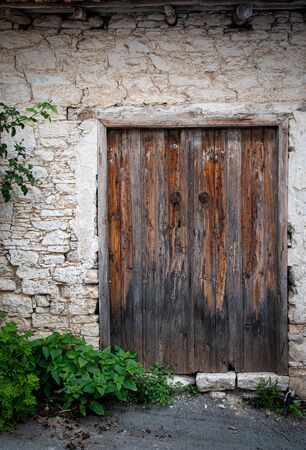 Entrance gate  of an abandoned house with a brown closed traditional Cyprus wooden doorの写真素材