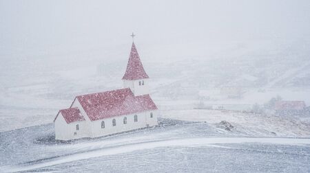 The picturesque Vik I Myrdal  church at the top of the hill during heavy snow at the village of vik in Iceland in winter.の写真素材