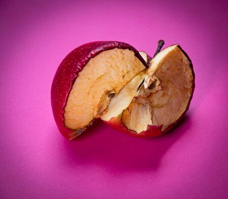 Fresh apple and slice of rotten unhealthy apple fruit isolated on a magenta background