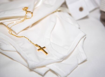 Gold small holy orthodox christening cross resting on a newborn  infant clothing during christening.の写真素材