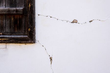 Closed vintage wooden window on a grungy white wall