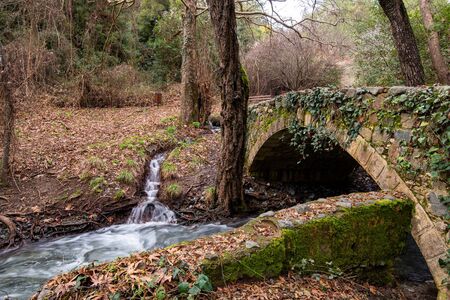 Beautiful medieval stoned bridge of Milia with river full with water flowing at Troodos mountains in Cyprusの写真素材