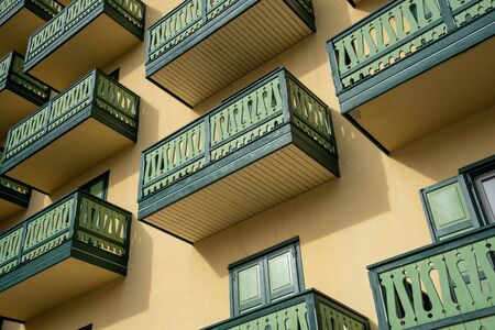 Beautiful Hotel balconies with green wooden vintage fences against a yellow wall.