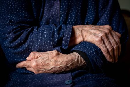 Elder woman crossing her wrinkled beautiful handsの写真素材