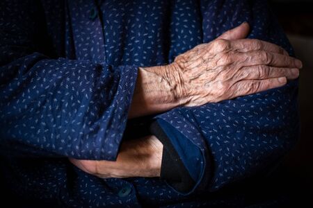 Elder woman crossing her wrinkled beautiful handsの写真素材
